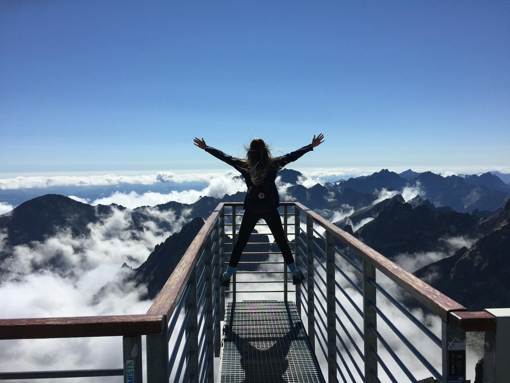 pexelsphoto725255 The Traini Counseling Group person standing on hand rails with arms wide open facing the mountains and clouds