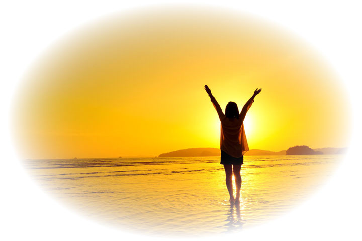 Silhouette of a person standing in shallow water at sunset with arms raised in triumph on a calm beach